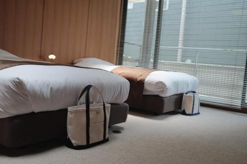 a hotel room with two beds and luggage at Law Firm ローファーム in Nagano