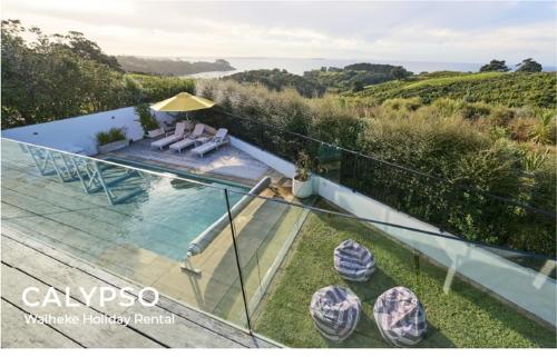 a view of a swimming pool from the balcony of a house at Calypso -Waiheke island Villa in Waiheke Island
