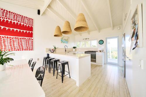 a kitchen with a white counter and stools at Calypso -Waiheke island Villa in Waiheke Island
