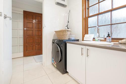 a kitchen with a washing machine and a sink at Magnolia on Colville - Historic Riverside Elegance in Hobart