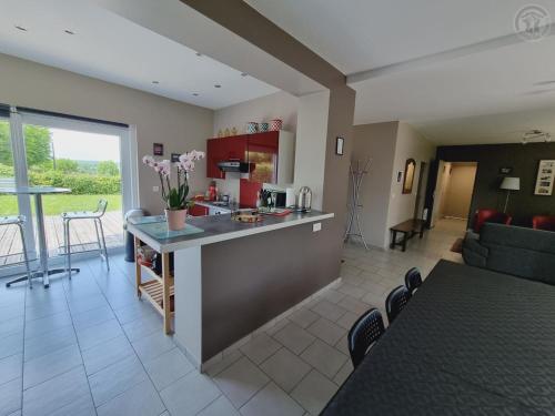 une cuisine et un salon avec une table et un canapé dans l'établissement Maison de charme avec grand dortoir, jardin privé et terrasse, proche Val Joly - FR-1-510-162, à Liessies