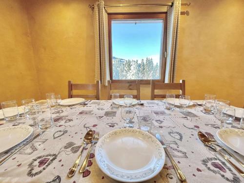 a table with plates and glasses on it with a window at Chalet indépendant avec spa, sauna et cheminée à Notre-Dame-de-Bellecombe - 10 pers - FR-1-595-102 in Notre-Dame-de-Bellecombe