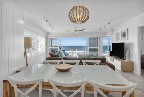 a living room with a white table and chairs at Rolling Surf Resort in Caloundra