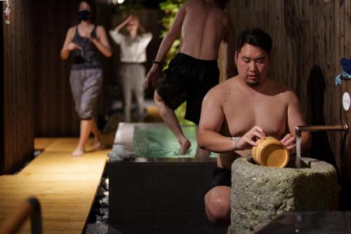a man sitting in a room holding a hat at 星空の降りそそぐ宿　金沢湯涌温泉 あたらしや in Kanazawa