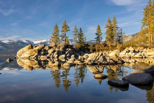 a lake with rocks and trees and mountains in the background at Mountain Getaway - Lake Tahoe - Incline Village - Private Garage in Incline Village