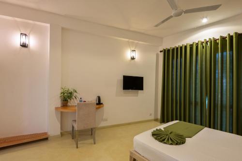 a bedroom with a bed and a desk and a television at Villa de Jojo in Galle