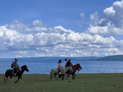 a group of people riding horses by the water at Jiguurten Aves 13 campground in Khyaktil