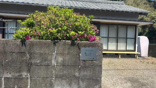 a retaining wall with a bush of flowers on it at Ichiya no jikka / Vacation STAY 78859 in Shimosato