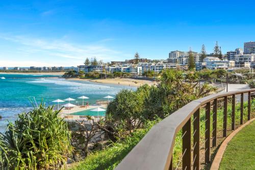 a bridge over a beach with buildings in the background at Rolling Surf Resort in Caloundra