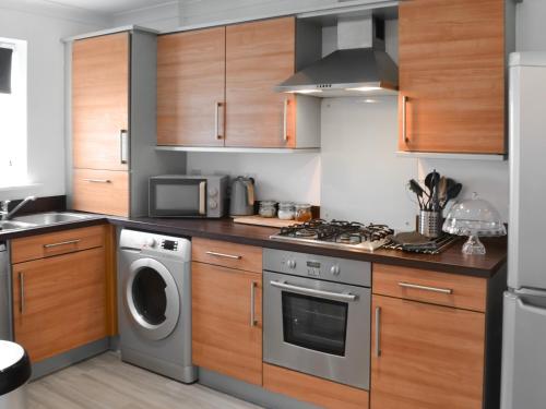 a kitchen with wooden cabinets and a washer and dryer at The Bandstand Sea View in Blythe