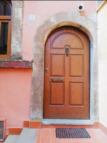 a wooden door on a pink building with an archway at La Casa di Gioia in Tuscania