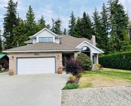 a house with a white garage door in a yard at The HI-Mark House - Hot tub,AC,Pool table, Pool May2026 in Sicamous