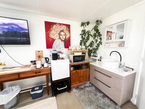 a kitchen with a sink and a desk with a microwave at Bed And Breakfast at Tirohanga Beach in Tirohanga