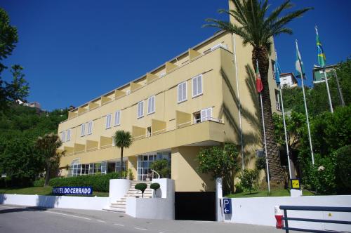 a yellow building with a palm tree in front of it at Hotel do Cerrado in Lamego