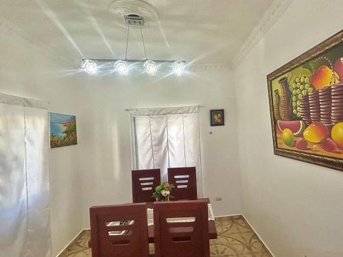 a dining room with a table and chairs and a painting at Villa Rosa 3 Habitaciones Balcones Aire Acondicionado Espacio Ideal Para Tu Familia O Grupo in Río San Juan