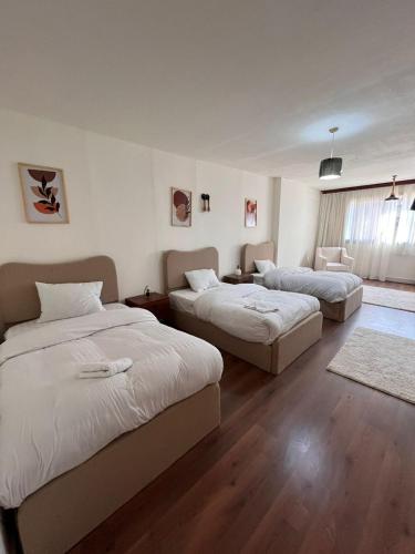 a bedroom with two beds and a living room at Zamalek Jedda tower 3BR in Cairo