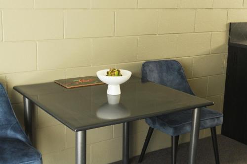 a table with two chairs and a bowl on it at City Close Motel in Napier