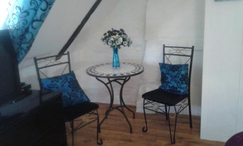 a table and two chairs with a vase of flowers on it at La Gerbaudiere Chambres&Table d hotes proche Mont Saint Michel CUISINE MAISON in Notre-Dame-du-Touchet
