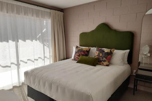 a bed with a green headboard in a bedroom at City Close Motel in Napier