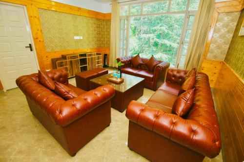 a living room with leather furniture and a large window at Verma Homestay by Decent stays in Shimla