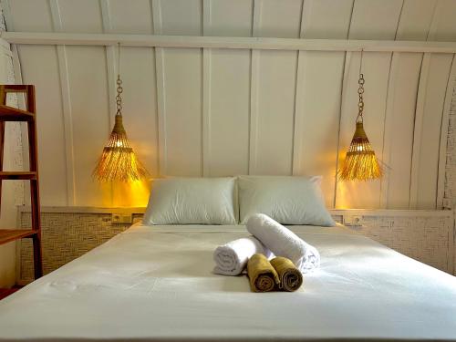 a white bed with two towels and two lights at Kelapa Lodge - Lombok - in Senggigi 