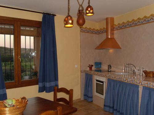 Casa Rural Del Antiguo Hojalatero في Ibdes: مطبخ مع طاولة وستارة زرقاء