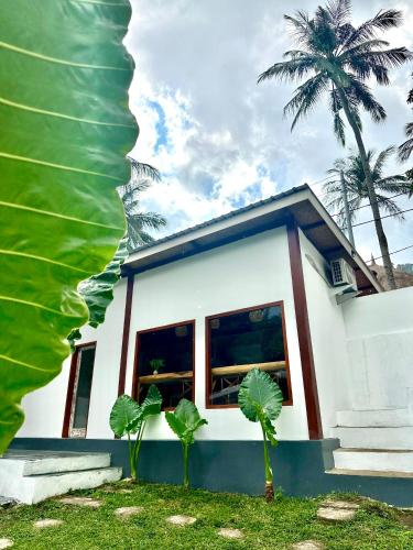 a small white house with palm trees in front of it at Kelapa Lodge - Lombok - in Senggigi 