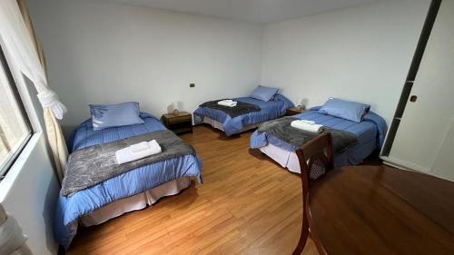 a room with three beds with blue comforters at Hotel Glaciares de Atacama in Copiapó