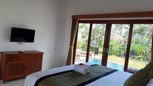 a bedroom with a bed and a tv and a window at Santika villa ubud in Ubud