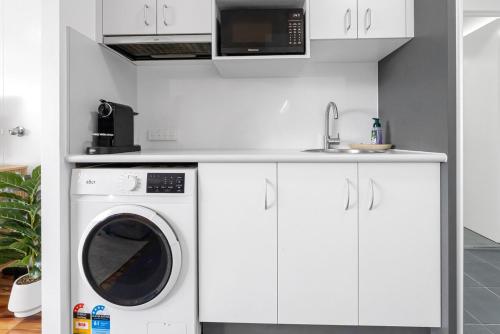 a white kitchen with a washing machine and a sink at Northshore Haven Studio in Cairns North