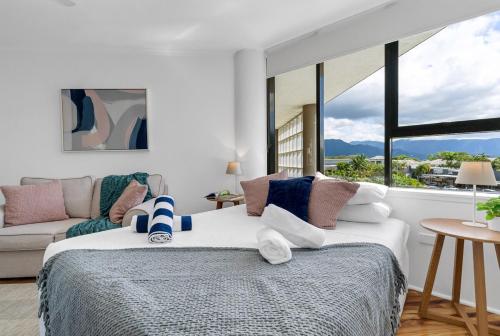 a bedroom with a bed and a couch and windows at Northshore Haven Studio in Cairns North