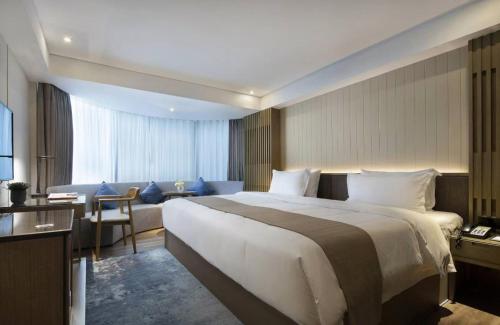 a hotel room with a large bed and a living room at 中濠s酒店福田口岸会展中心店 in Shenzhen