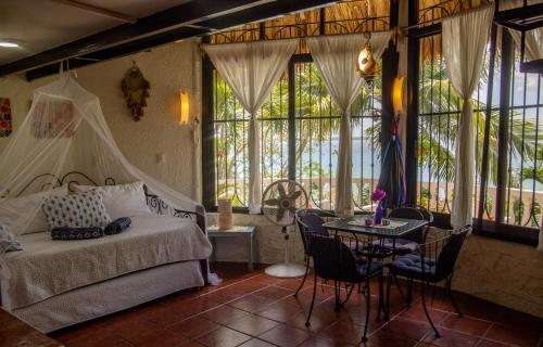 Un dormitorio con una cama y una mesa y ventanas. en Dog Friendly Villas Pehaltun Bacalar, en Bacalar