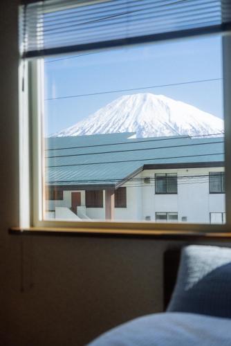 a view of a snow covered mountain through a window at Niseko Pink house in Kutchan
