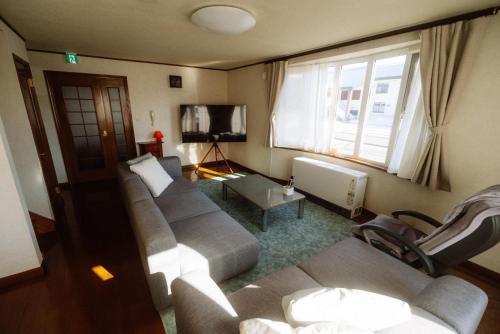 a living room with couches and a flat screen tv at Niseko Pink house in Kutchan
