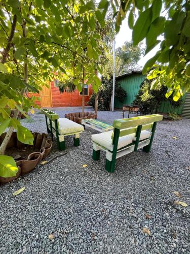 three park benches sitting on the ground under a tree at Entre Ríos, Santa Cruz 