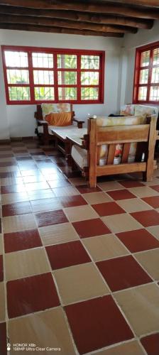 a room with a checkered floor with benches and windows at Finca La Vistosa in Sasaima