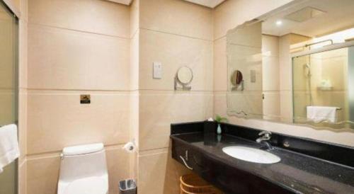 a bathroom with a sink and a toilet and a mirror at Fuzhou Xin Zi Yang Hotel in Fuzhou