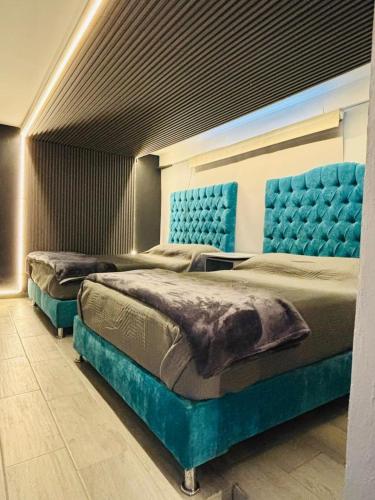 two beds in a room with blue tufted beds at Depa Frente al aeropuerto hasta 12 Huéspedes in Mexico City