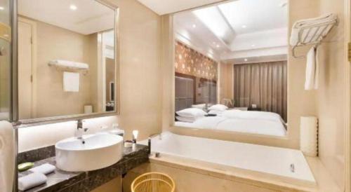 a bathroom with a sink and a large mirror at Jinjiang Grandlink Hotel in Quanzhou