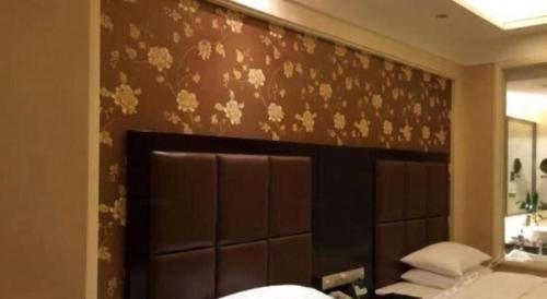 a bedroom with a brown wall with flowers on it at Jinjiang Grandlink Hotel in Quanzhou