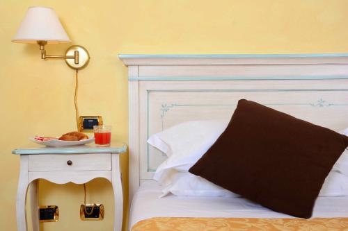 a bed with a white headboard and a plate of food on a side table at Albergo Dimora Storica Antica Hostelleria in Crema