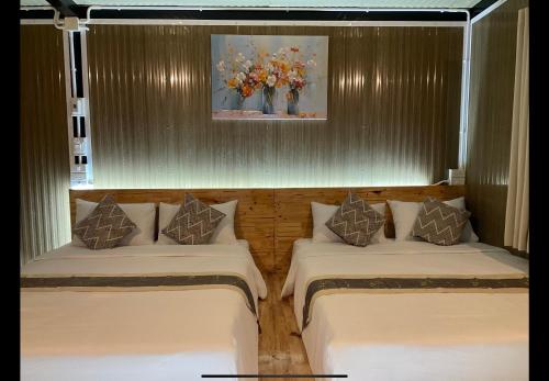 two beds in a room with a vase of flowers at The will glamping&camping in Ban Na Pho