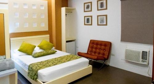 a bedroom with a bed and a red chair at Hotel Monde in Dagupan