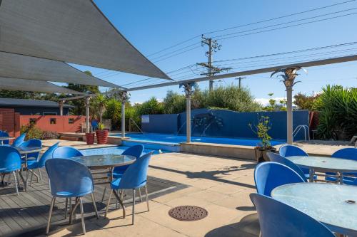 a patio with tables and chairs and a swimming pool at Riverside Hotel Marlborough in Blenheim