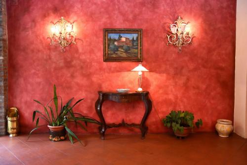 a red wall with a table in a room with plants at Albergo Dimora Storica Antica Hostelleria in Crema