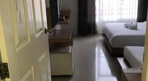 a room with two beds and a door and a room with a bed sidx sidx at Tonkok Hotel in Chiang Rai