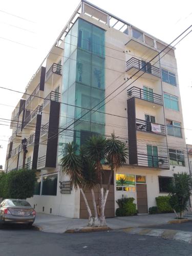 a building with a palm tree in front of it at Depa Frente al aeropuerto hasta 12 Huéspedes in Mexico City