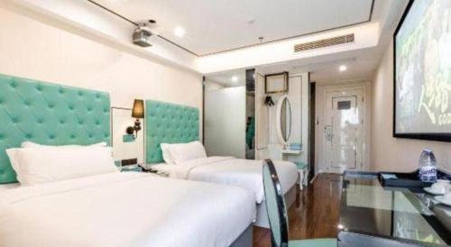 a hotel room with two beds and a television at Xana Lite Anqing Yuexi Swan Squre Branch in Yuexi