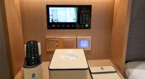 a room with a telephone and a tv on the wall at East Queen Hotel (Xi'an Beimen Metro Station) in Xi'an